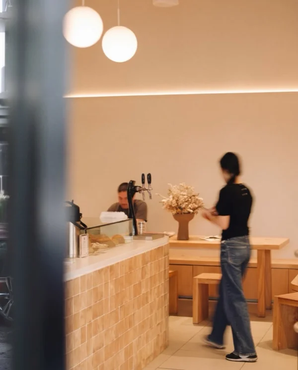 Inside Noia Coffee Co — warm timber counter, globe pendants, and barista in motion at Rozelle Sydney